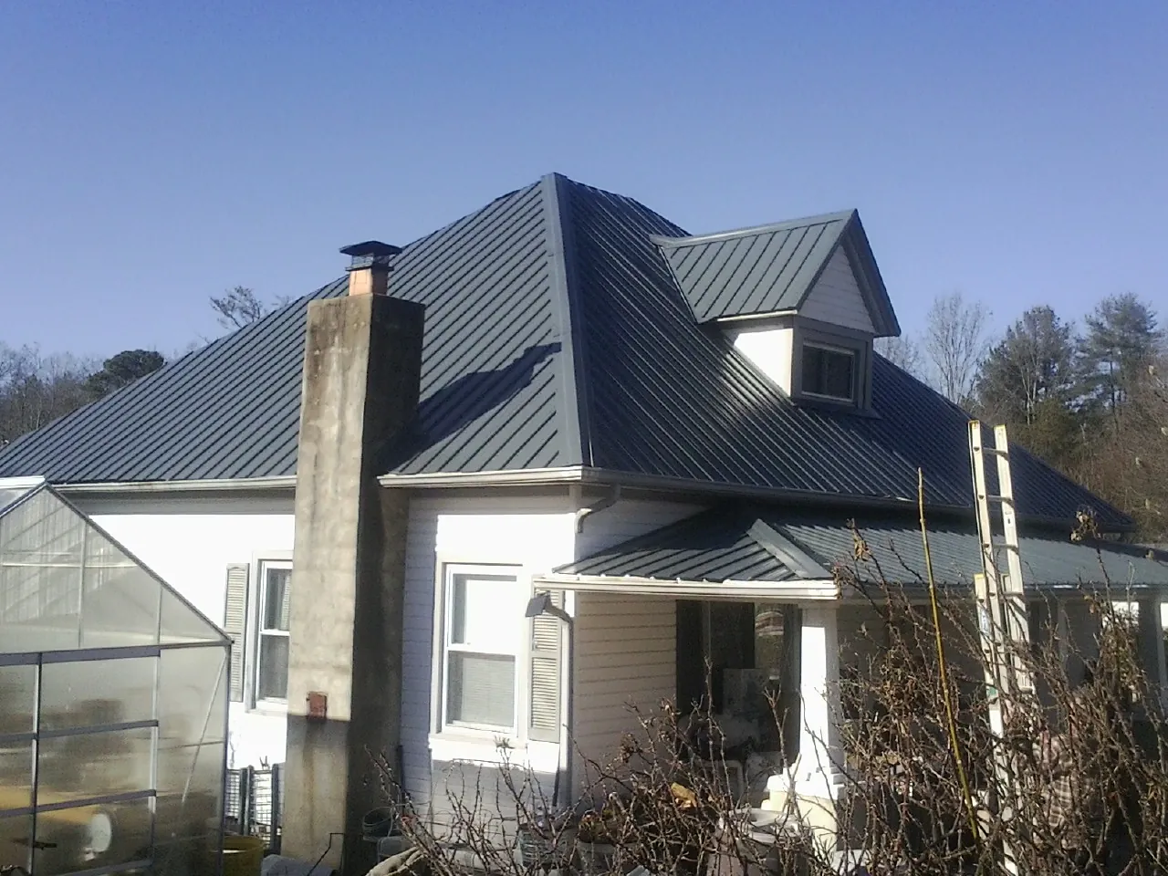 Dark blue standing seam metal roof on a white farmhouse with dormer — Slate & Tile Roof Repair by Roofing Brothers in North Bonneville