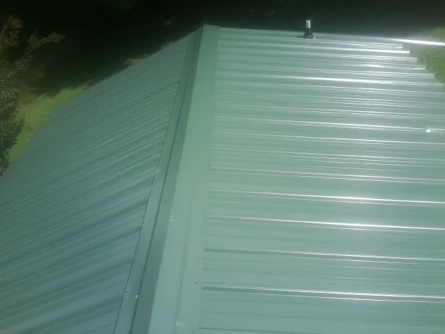New green metal panels meeting at the ridge of a roof — Flat Roof Repair work by our crew in North Bonneville