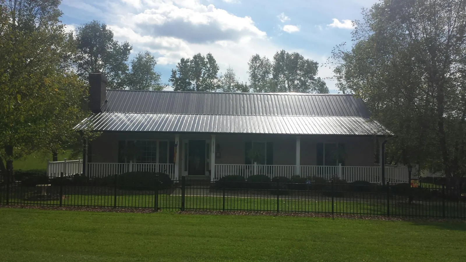 Gray metal roof on a brick ranch with a full width front porch — Gutter Guard Installation work by our crew in North Bonneville