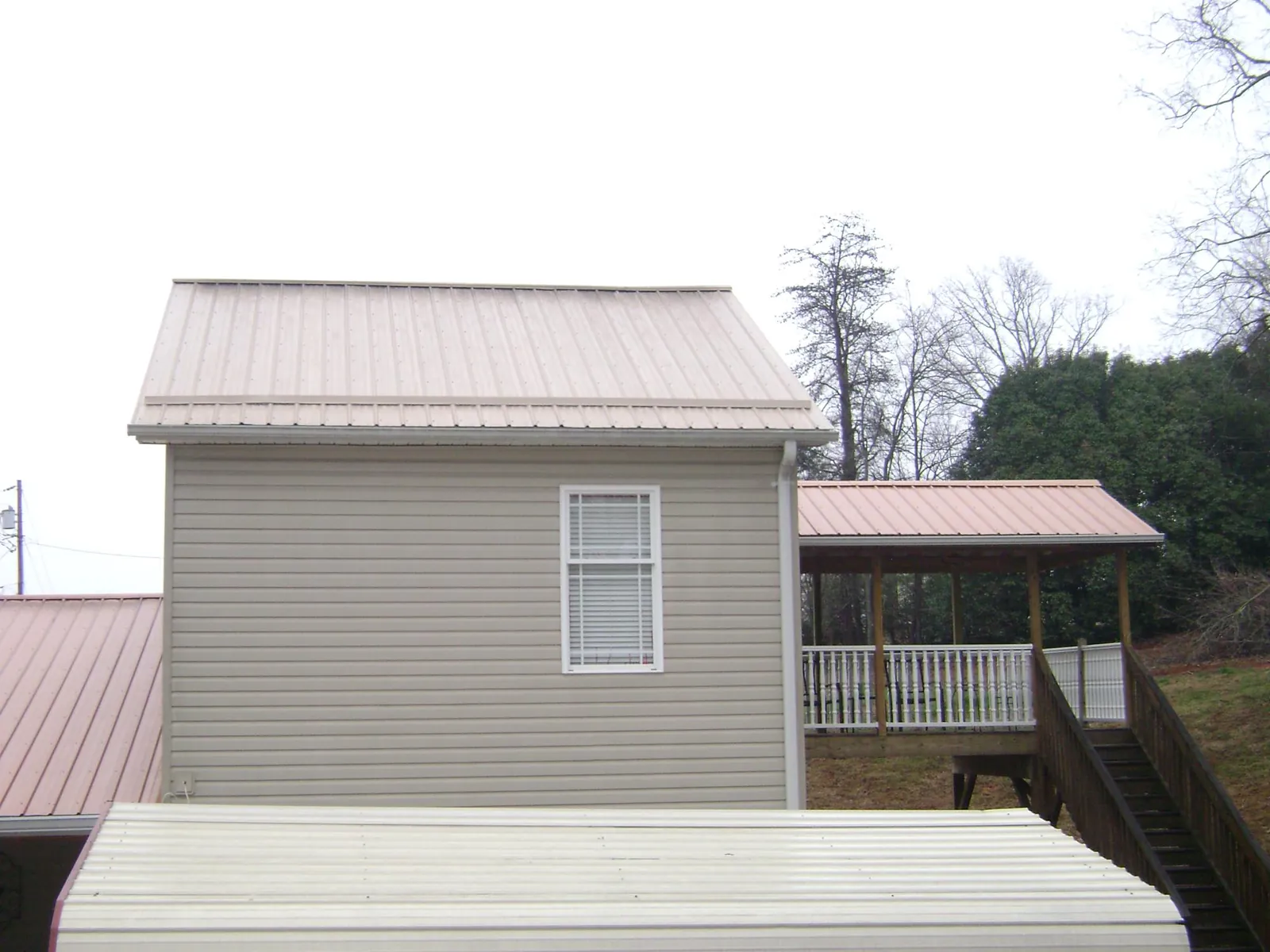 Tan metal roofs on a two story addition and attached porch, from a Roof Replacement job in North Bonneville