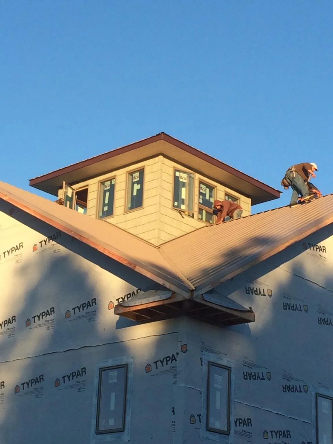 Roofers working around a rooftop cupola on a new metal roof at sunset — Roof Waterproofing in North Bonneville by Roofing Brothers